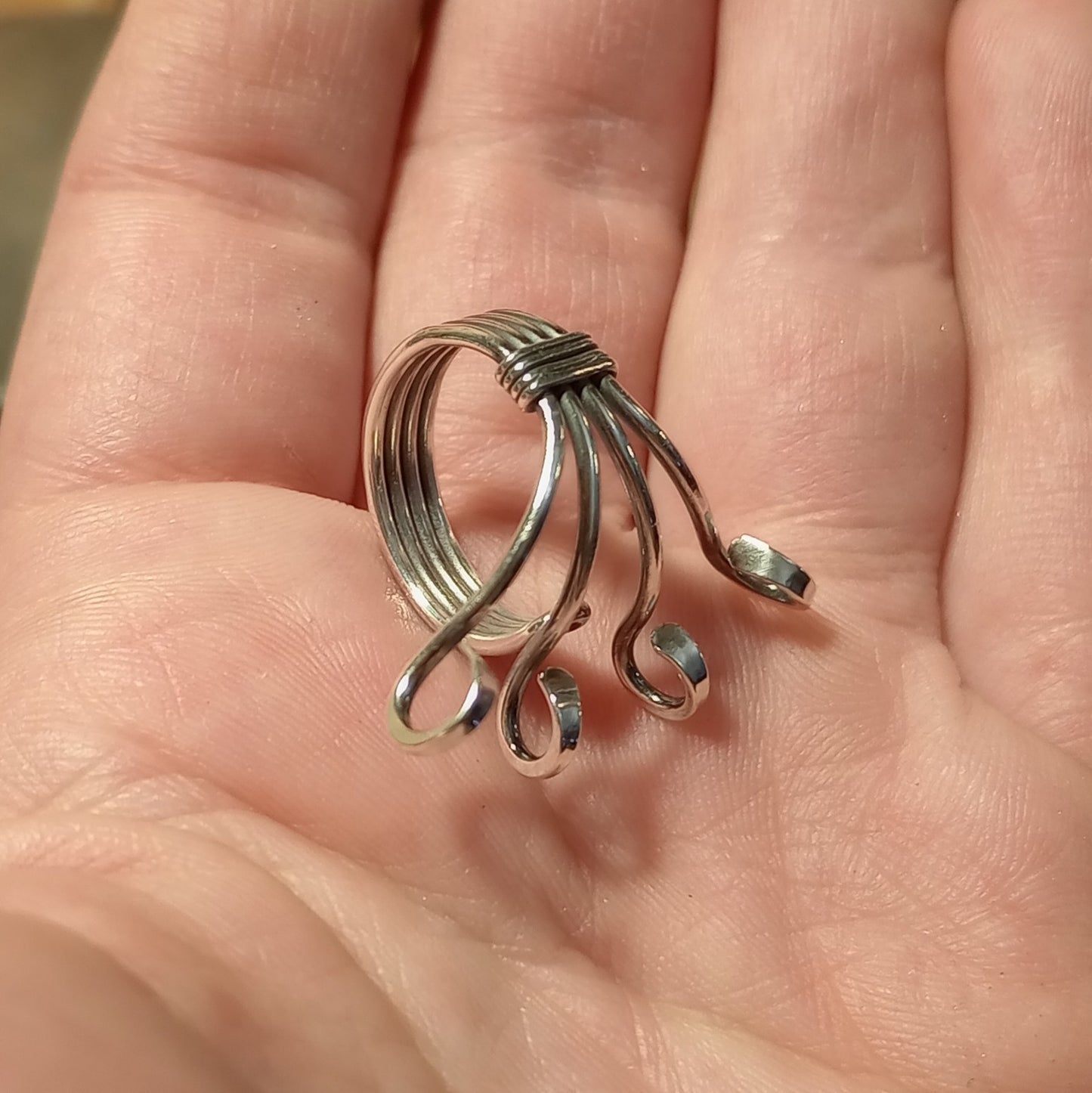 Silver yarn guide ring with four hooks held in hand
