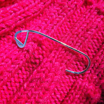 a silver shawl pin on pink knitted fabric