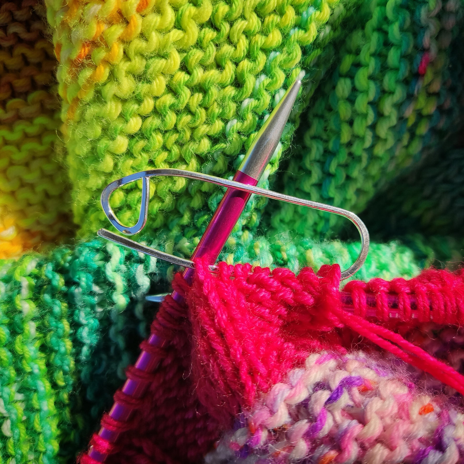 a silver stitch holder on colourful knitting