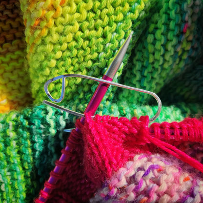 a silver stitch holder on colourful knitting